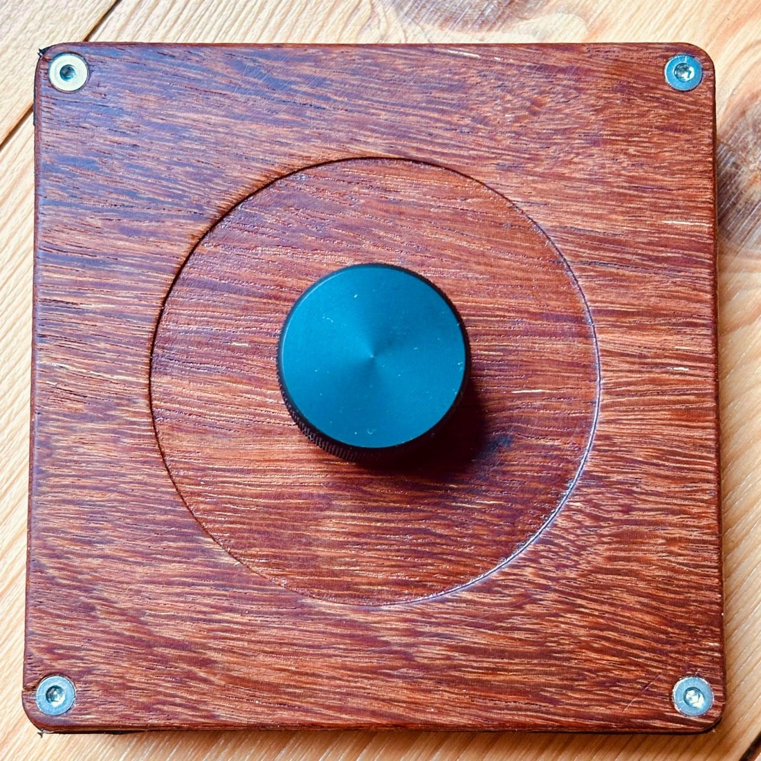 Top view of TrigOne Mini showing the wood grain, four screws, and central encoder